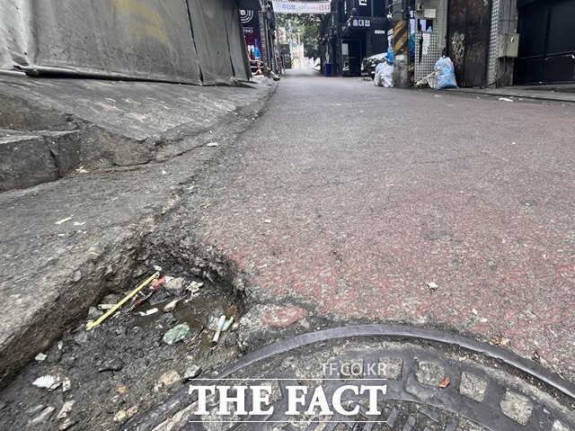 서울 마포구 홍대 포차골목 아래쪽에 홈이 파여 물과 쓰레기 등이 고여있다. /황지향 기자