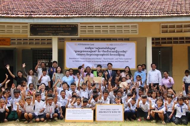 7일 캄보디아 프놈펜에서 진행된 기부 물품 전달식에서 KB국민카드 현지법인 KB대한특수은행 임직원들과 운롱깐초등학교 아이들이 기념 촬영을 하고 있다. /KB국민카드