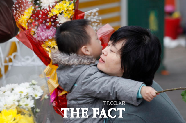 한 여성이 지난해 11월 16일 북한 평양에서 어머니날을 맞아 꽃을 건넨 아들을 안아주고 있다. / AP.뉴시스