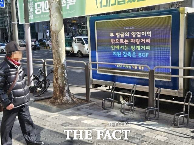 26일 오후 서울 강남구 삼성동 BGF리테일 본사 앞에 직원들이 트럭 시위를 시작한 가운데 한 시민이 전광판을 바라보고 있다. /삼성동=우지수 기자