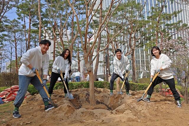장재훈 롯데물산 대표이사(오른쪽에서 두 번째)와 임직원 봉사자들이 석촌호수 동호 주변 녹지에 나무를 심고 있다. /롯데물산
