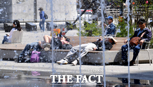 휴양지 못지 않네~ 시민들이 바닥분수 앞에 누워 휴식을 취하고 있다.