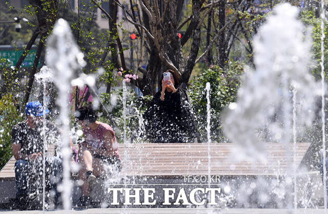 4월 마지막 날인 30일은 낮 최고 26도로 평년과 비슷하거나 조금 높겠다. 중부지방(강원영동 제외)은 가끔 구름많겠으나 강원영동과 남부지방, 제주는 대체로 흐리고, 일부 지역에서는 소나기가 오는 곳이 있겠다. 사진은 서울 광화문 광장을 찾은 한 여성이 바닥분수를 촬영하고 있는 모습.