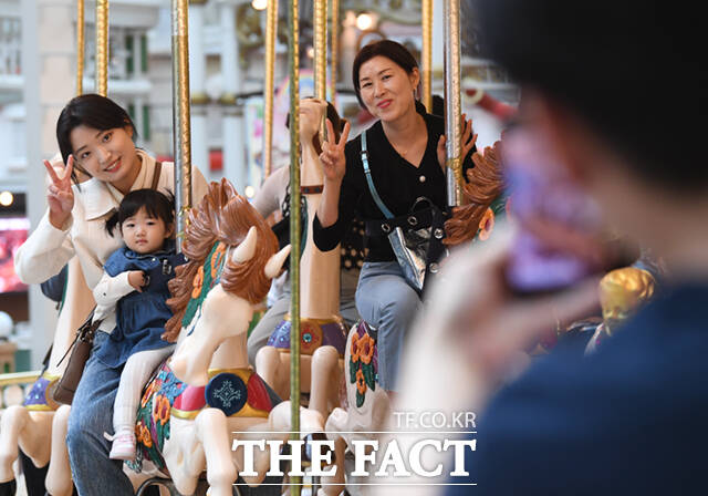 어린이날 대체공휴일인 6일 서울 송파구 잠실동 롯데월드 어드벤처를 찾은 가족들이 회전목마를 타며 기념촬영하고 있다.