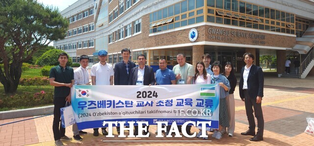 ‘우즈베키스탄 교사 초청 교육 교류’에 참여한 우즈베키스탄 교사 및 관계자들이 북구 첨단과기로에 위치한 광주과학고등학교 본관 앞에서 현수막을 들고 포즈를 취하고 있다./ 광주송정다가치문화도서관