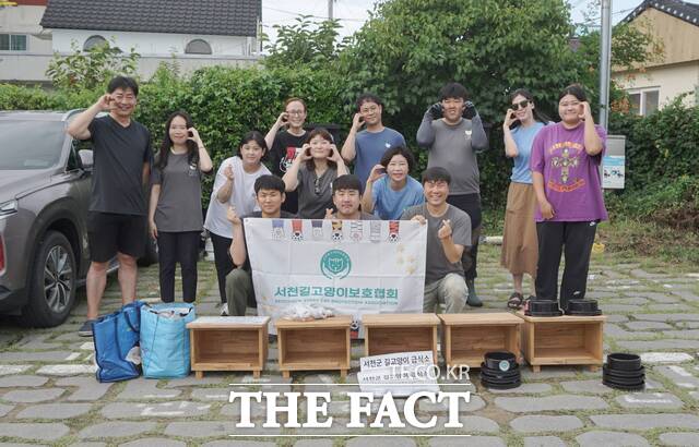 서천군 서천길고양이보호협회가 서천읍 한 공영주차장에서 길고양이 공공급식소를 설치하며 기념촬영을 하고 있다. / 서천군