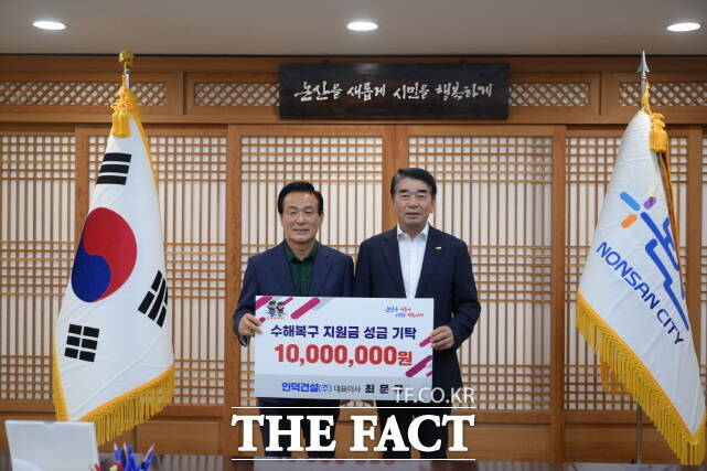 최문규 인덕건설 대표(오른쪽)가 백성현 논산시장에게 1000만 원의 수재의연금을 전달하고 있다. /논산시