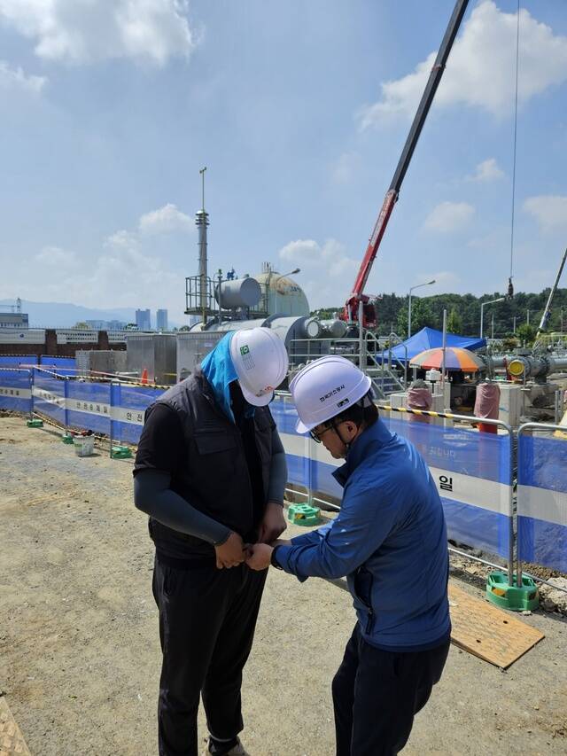 김환용 한국가스공사 안전기술부사장(오른쪽)이 현장 근로자에게 아이스 조끼를 입혀주고 있다. /한국가스공사