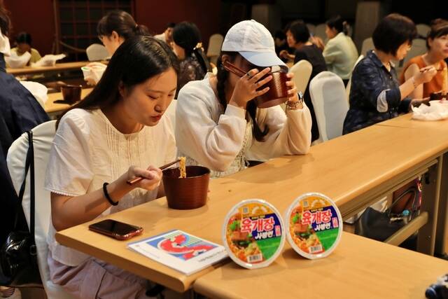 농심 케잇데이 참가자들이 국가무형유산 칠장 안소라 이수자가 직접 만든 옻칠 면기와 젓가락으로 농심 라면을 시식하는 모습. /농심