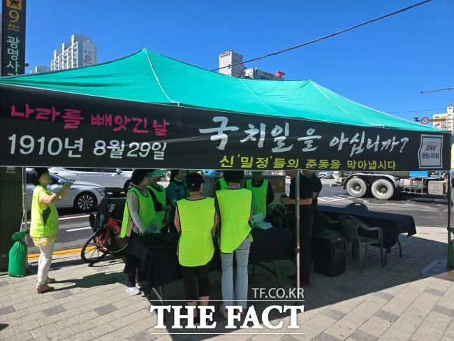 29일 경기 광명역사거리 일대에서 광복회 광명시지회 회원들이 신 ‘밀정’들의 준동을 막아냅시다라고 쓰인 그늘막 아래서 시민들에게 경술국치 유인물과 흰죽을 나누고 있다./광명시