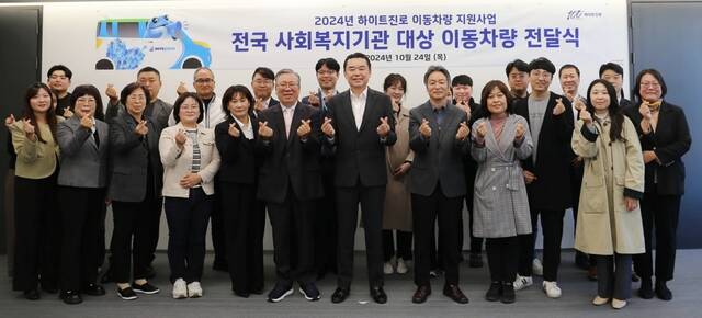 지난 24일 서울시 서초구 하이트진로 사옥에서 열린 취약계층의 이동 편의성을 위한 이동차량 전달식에서 김인규 하이트진로 대표(앞줄 오른쪽 네 번째)와 전국 13개 사회복지기관 대표 및 관계자들이 기념 촬영하고 있다. /하이트진로