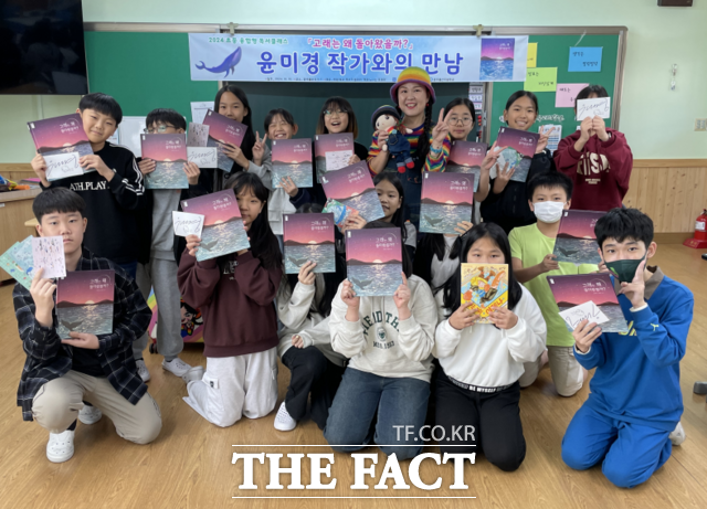 광주서부교육지원청 주관 ‘학교로 찾아가는 작가 수업’에 참여한 윤미경 작가와 월산초 학생들이 작가의 ‘고래는 왜 돌아왔을까’를 들고 환하게 웃고 있다. 사진은 지난 10월 10일 월산초 5,6학년 대상 수업 후 단체사진/ 광주서부교육지원청