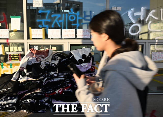 성신여대 학생들이 남학생 입학 허용 철회를 요구하며 대규모 시위를 벌이는 가운데, 건물 한켠에 학생들이 벗어놓은 대학점퍼가 쌓여 있다.