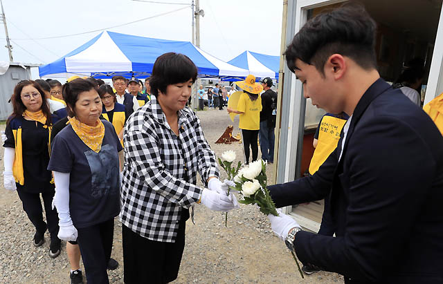 3일 오후 전남 진도군 임회면 팽목항에 설치됐던 세월호 참사 희생자 분향소가 철거되는 가운데 유가족들이 마지막 헌화를 앞두고 국화꽃을 건네받고 있다. /팽목항(진도)=뉴시스