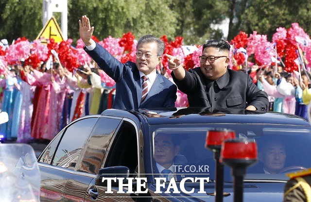 문재인(왼쪽) 대통령과 김정은 국무위원장이 18일 평양 순안공항에서 백화원 초대소로 이동하며 시민들을 향해 인사를 하고 있다. /평양사진공동취재단