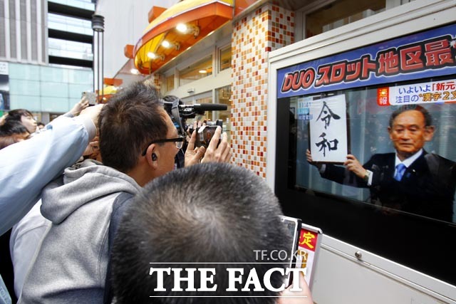 지난 1일 도쿄 시민들이 스가 요시히데 일본 관방장관의 새로운 연호 ‘레이와(令和)’ 발표 중계방송을 시청하며 사진을 찍고 있다. /AP.뉴시스