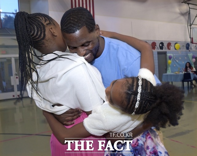 지난 8월 미 코네티컷주 엔필드의 윌라드-시불스키 교정센터에서 가족 무도회가 열려 수감자 타이런 패터슨(가운데)가 자신의 두 딸과 춤추며 포옹하고 있다. /뉴시스