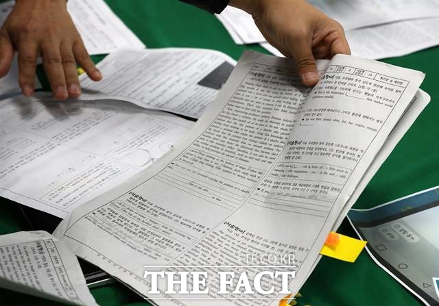 교사인 아버지가 유출한 답안으로 공부해 시험을 치른 혐의를 받는 쌍둥이 자매 중 한 명이 항소심 취재진에게 손가락 욕을 했다. 사진은 경찰 수사 당시 압수된 시험지 등 증거물들./뉴시스
