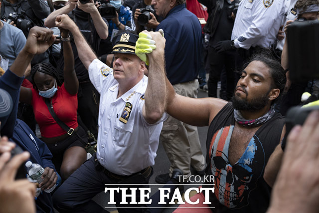 1일(현지시간) 미국 뉴욕에서 조지 플로이드의 죽음에 항의하는 시위대가 시위를 잠시 멈춘 사이 테렌스 모나한 뉴욕시 경찰서장이 한 운동가와 함께 무릎을 꿇고 손을 맞잡고 있다.