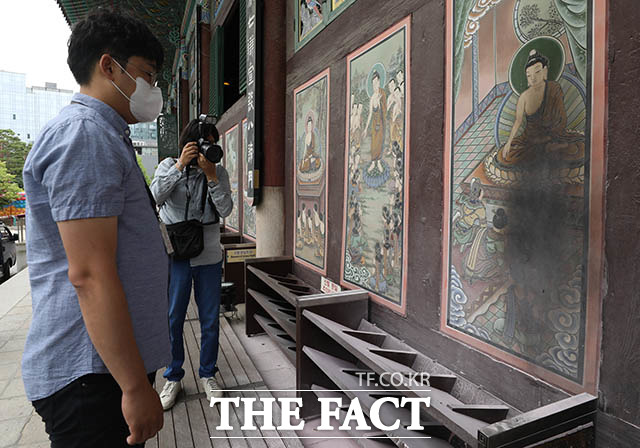 조계종 관계자가 19일 서울 종로구 조계사 대웅전에서 훼손된 외벽 벽화를 보고 있다. /뉴시스