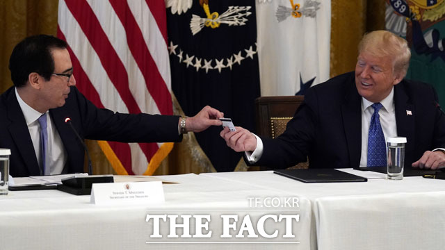 도널드 트럼프 미국 행정부와 공화당이 신종 코로나바이러스 감염증 대응을 위해 1조 달러(약 1200조 원) 규모의 추가 경기부양안을 추진하기로 했다. 사진은 트럼프 대통령(오른쪽)이 지난 19일(현지 시간) 워싱턴 백악관 이스트룸에서 열린 내각회의 도중 스티븐 므누신 재무장관으로부터 재무부가 국민들에게 지급할 재난지원 현금카드를 전달받는 모습. /워싱턴=AP·뉴시스