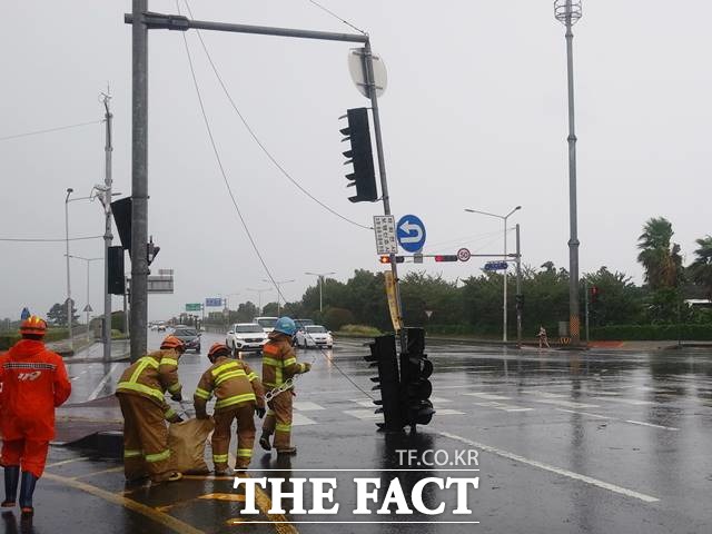 제8호 태풍 ‘바비의 강풍으로 26일 오전 제주시 연동 마리나호텔 사거리에서 신호등이 도로에 쓰러져 출동한 소방대원들이 안전조치를 하고 있다. /뉴시스