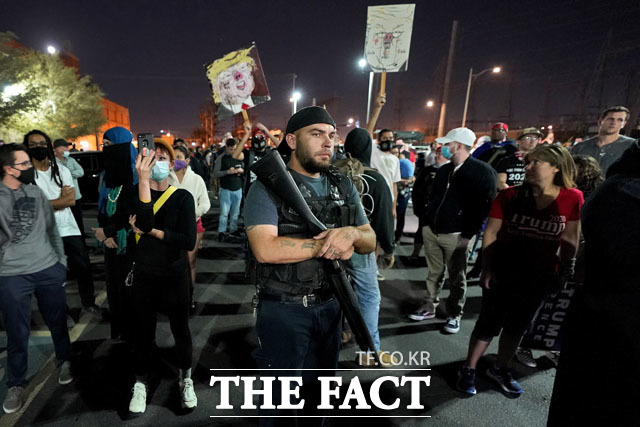 트럼프 대통령 지지자들 사이에서 총기를 들고 서 있는 남성.