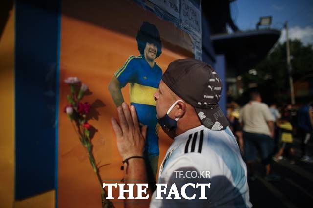 아르헨티나 축구팬이 보카 주니어스 스타디움의 마라도나 포스터에 입을 맞추며 축구 영웅의 별세를 애도하고 있다./부에노스아이레스(아르헨티나)=AP.뉴시스