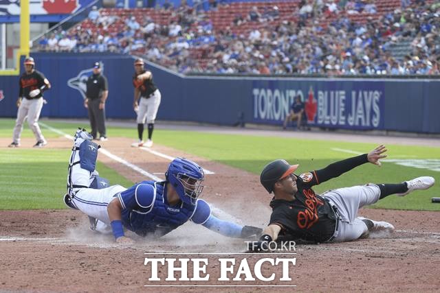 6회까지 무실점 피칭을 이어가던 류현진이 7회 초 집중력이 흔들리며 실점하는 장면. 토론토 홈 송구가 치우치며 볼티모어 주자가 포수 매과이어의 태그를 피해 득점하고 있다./버펄로=AP.뉴시스