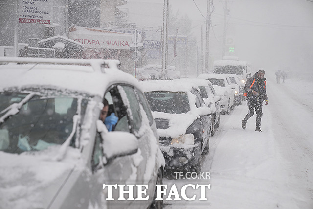 24일 (현지시각) 그리스 아테네 북쪽 아기오스 스테파노스에 눈이 내리는 동안 도로의 차량이 거북이 운행을 하고 있다. 악천후가 25일까지 계속될 것으로 예보되면서 당국은 시민들에게 불필요한 외출을 자제할 것을 촉구했다. /아테네=AP.뉴시스