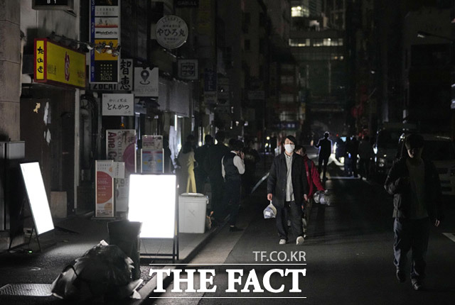 지진으로 인해 간토와 도호쿠 지방에 대규모 정전이 발생한 가운데 도쿄에서 사람들이 암흑이 된 거리를 지나고 있다.