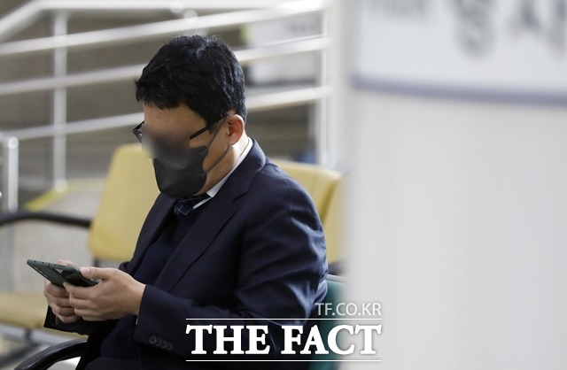 고 김홍영 검사를 폭행한 혐의를 받고 있는 김대현 전 부장검사가 18일 서울중앙지방법원에서 열린 항소심 1차 공판에 출석하기 전 벤치에 앉아 휴대폰을 보고 있다. /뉴시스