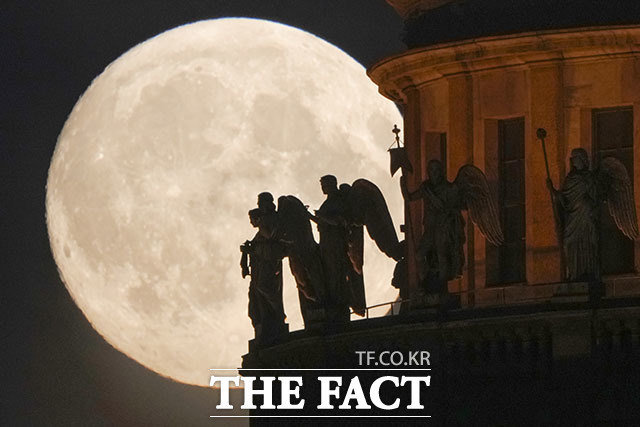 13일(현지시간) 러시아 상트페테르부르크의 성 이사크 대성당 천사 조각상 너머로 환한 보름달이 빛을 내뿜고 있다. /상트페테르부르크=AP.뉴시스