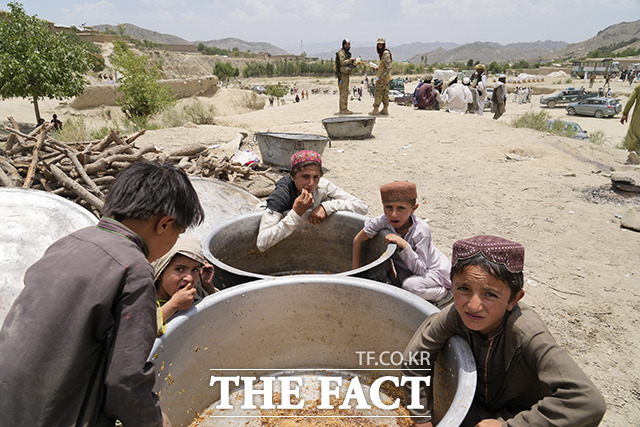지진 피해를 입은 아프가니스탄 팍티카주 가얀 마을 어린이들이 26일(현지시간) 마을 지진 난민 수용소에서 배급 밥솥의 남은 밥알을 긁어 모으고 있다./AP.뉴시스