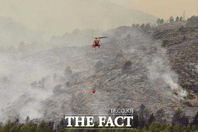 17일(현지시간) 스페인 비베르에서 산불로 인한 연기가 치솟고 있는 가운데 소방 헬기가 산불을 진압하고 있다. /비베르=AP.뉴시스