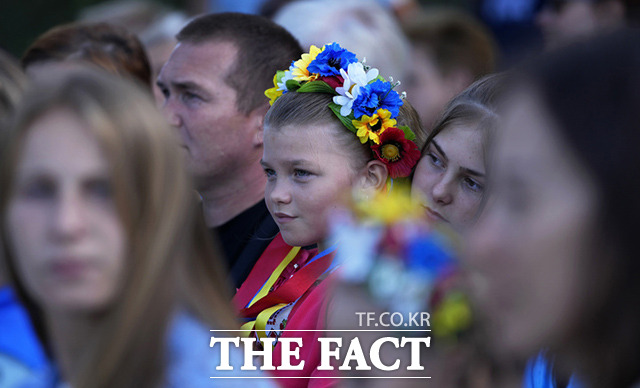 포르투갈에서 열린 우크라이나 독립기념일 기념식에 참석한 한 아이가 우크라이나 국기 색상으로 만들어진 꽃화관을 착용하고 있다. /리스본=AP.뉴시스