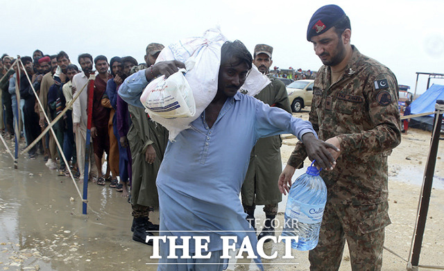 파키스탄 전역에 내린 물폭탄으로 인해 230만명이 넘는 이재민이 발생했다. 구호소에서 파키스탄 군인들이 이재민에게 음식 등 구호품을 나눠주고 있다. /잠쇼로=AP.뉴시스