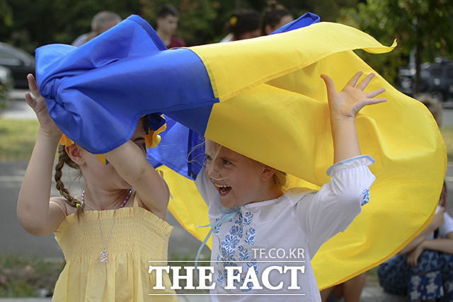 루마니아 부쿠레슈티에서 우크라이나 국기를 들고 뛰어다니는 우크라이나 난민 어린이들. /부쿠레슈티=AP.뉴시스