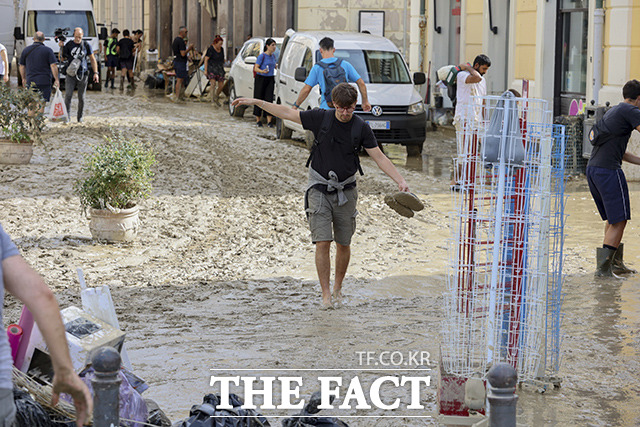 16일(현지시간) 이탈리아 중부 마르케주 세니갈리아에 내린 집중 호우로 홍수가 발생하면서 주민들이 거리를 뒤덮은 진흙은 치우고 있다. /세니갈리아=AP.뉴시스