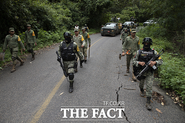 멕시코에서 규모 7.6의 강진이 발생한 가운데 20일(현지시간) 멕시코의 군인들이 지진 피해 복구를 위해 미초아칸주 치니쿠일라의 부서진 도로 위를 걷고 있다. /치니쿠일라=AP.뉴시스