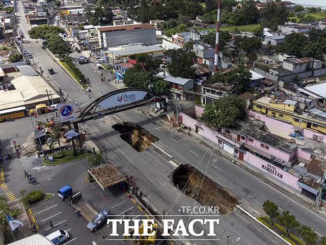 25일(현지시간) 과테말라 비야누에바의 한 도로에 거대한 싱크홀이 발생해 구조대원들이 구조작업을 벌이고 있다. /비야누에바=AP.뉴시스