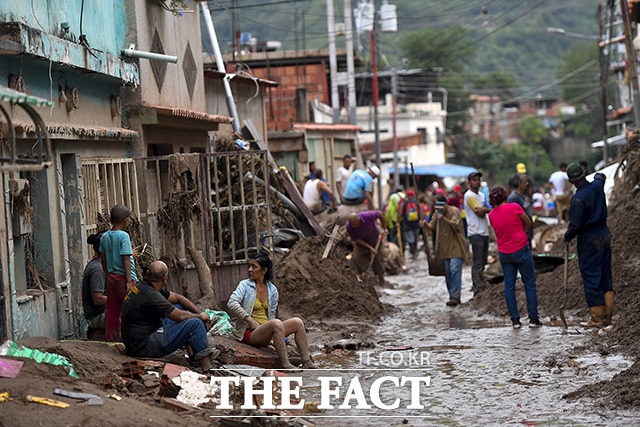 9일(현지시간) 대규모 산사태가 발생한 베네수엘라 아라과주 라스테헤리아스 산간 마을에 주민들이 거리를 뒤덮은 진흙더미를 치우기 위해 모여 있다. /라스테헤리아스=AP.뉴시스