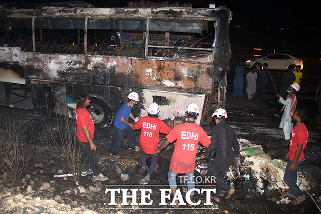 13일(현지시간) 파키스탄 남부 신드주의 잠쇼로 지역의 고속도로를 달리던 카라치행 버스에서 화재가 발생한 가운데 구조대원과 자원봉사자들이 사고현장을 수습하고 있다. /카라치=AP.뉴시스