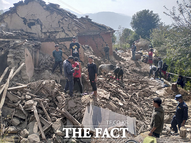9일(현지시간) 네팔 서부 산악지대 도티 지역에서 규모 5.6의 강진이 발생한 가운데 주민들이 무너진 가옥 잔해 속에서 대화를 나누고 있다. /도티=AP.뉴시스
