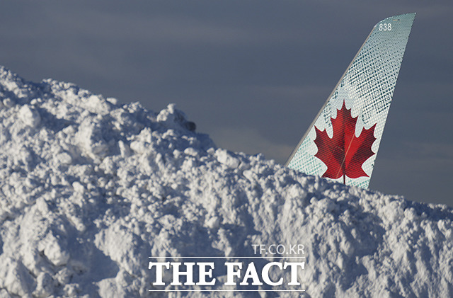 21일(현지시간) 캐나다 브리티시컬럼비아주 리치먼드에 위치한 밴쿠버 국제공항에서 치운 눈 더미 뒤로 에어 캐나다 항공기의 꼬리날개가 보이고 있다./벤쿠버=AP.뉴시스