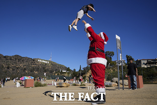 산타클로스 복장을 한 남성이 미국 로스앤젤레스 레이크 할리우드 파크에서 아이와 함께 즐거운 시간을 보내고 있다./LA=AP.뉴시스