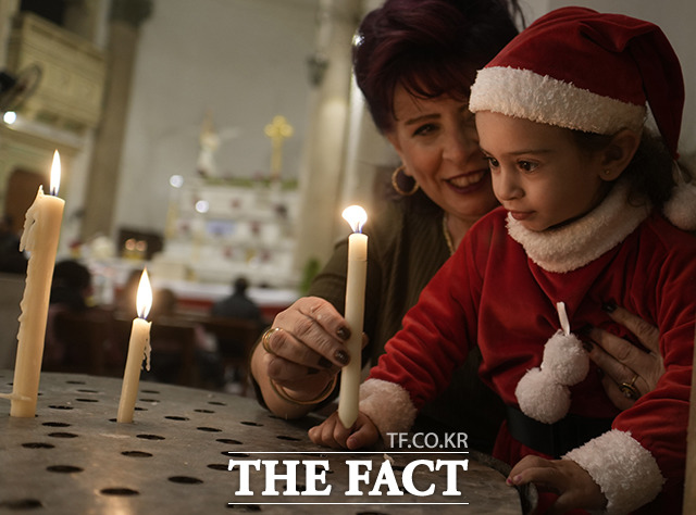 아기 예수의 탄생을 축하하는 크리스마스를 맞은 가운데 세계 곳곳에서 축제가 열렸다. 크리스마스 이브인 24일(현지시간) 산타 복장을 하고 이집트 카이로의 성 요셉 성당을 찾은 한 어린이가 크리스마스 이브 미사에서 촛불을 밝히고 있다./카이로=AP.뉴시스