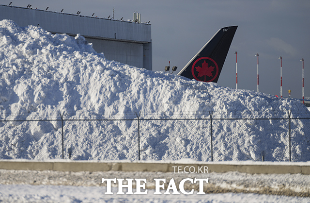 21일(현지시간) 캐나다 브리티시컬럼비아주 리치먼드에 있는 밴쿠버 국제공항에서 치운 눈 더미 뒤로 에어 캐나다 항공기의 꼬리날개가 보이고 있다. /리치먼드=AP.뉴시스