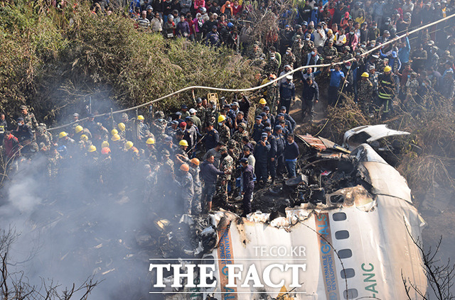 15일(현지시간) 네팔 포카라의 신축 공항 인근에서 여객기 추락 사고가 발생한 가운데 산산조각 난 여객기 근처로 구조대와 민간인들이 모여 있다. /포카라=AP.뉴시스