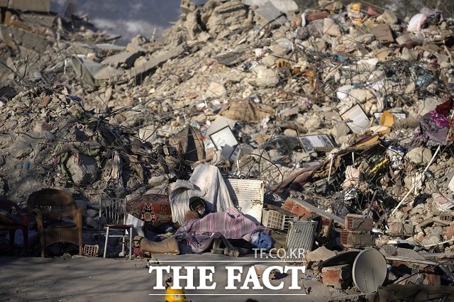 카라만마라슈에서 한 주민이 지진으로 파괴된 건물 잔해 주변에 누워 있다. /카라만마라슈=AP.뉴시스